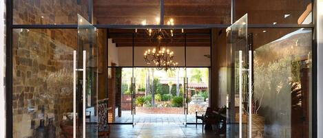 A modern entrance with stone walls, a chandelier, and a patio area visible through glass doors.