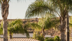Een stenen fontein omringd door tropische planten en een betegelde pergola.