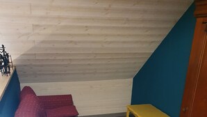 Een kamer met een rode bank, een gele tafel en een houten kast.