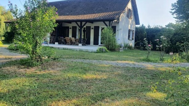 Een twee verdiepingen tellend huis met een pannendak en een overdekte veranda.