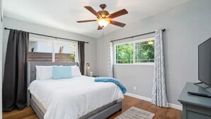 A bedroom with a bed, a ceiling fan, a window with curtains, a television, and a wooden floor. - Close to Downtown! Gorgeous MidCentury w/fire pit (Paso Robles)