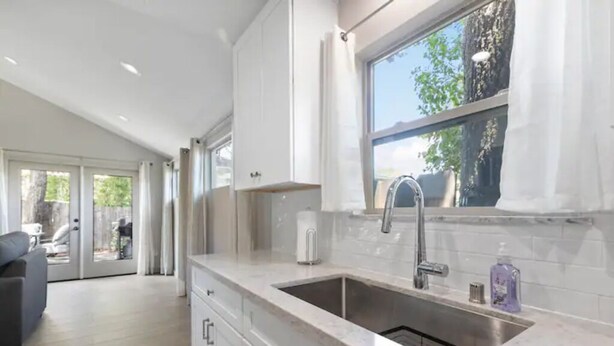 A modern kitchen with white cabinets, a large window, and a built-in sink. - Lovely Remodeled Home! Walk Downtown! w/firepit (Paso Robles)