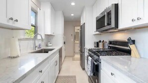 A modern kitchen with white cabinets, stainless steel appliances, and a marble countertop. - Lovely Remodeled Home! Walk Downtown! w/firepit (Paso Robles)