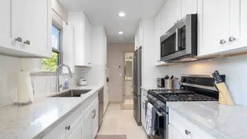 Una cocina moderna con armarios blancos, electrodomésticos de acero inoxidable y una encimera de mármol.