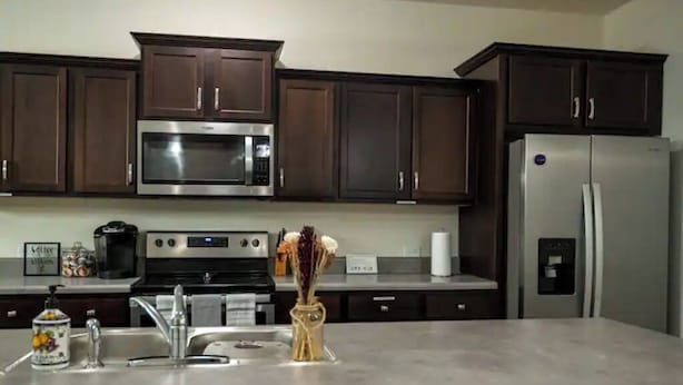 A modern kitchen with dark wooden cabinets, stainless steel appliances, and a granite countertop. - Gorgeous Entire Home In Greensboro!!!! (Greensboro)