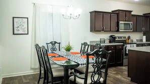 A dining area with a glass-top table, black chairs, and a chandelier. - Gorgeous Entire Home In Greensboro!!!! (Greensboro)
