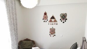 Un lit double avec une literie bleue et blanche, une table de chevet avec une lampe et un coquillage décoratif, et des œuvres d’art murales au-dessus du lit.
