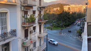 Un immeuble à plusieurs étages doté de balcons, une enseigne bien visible indiquant « Piano Mobile », et une vue sur la rue avec des voitures et un passage piéton.