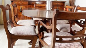 Une salle à manger avec une table ronde en bois, entourée de six chaises rembourrées recouvertes d’un tissu à motifs.