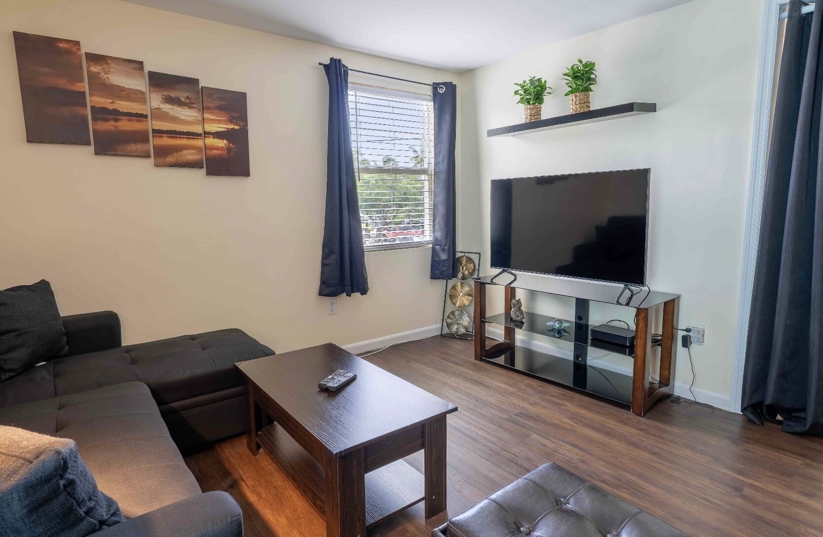 Ein Wohnzimmer mit einer Couch, einem Couchtisch, einem Fernseher auf einem Lowboard und Kunstwerken an der Wand.