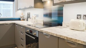A modern kitchen with a marble countertop, built-in oven, and a toaster. - Hollins on the Coast (Bridlington)