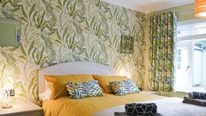 A bedroom with a bed, two pillows, a bedside table, a lamp, and a window with curtains. - Hollins on the Coast (Bridlington)