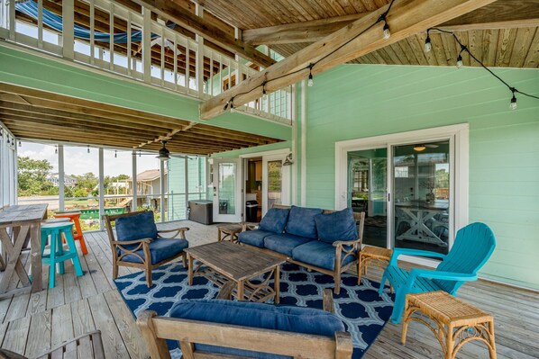 Un espace extérieur aménagé, abrité, avec des meubles en bois et un tapis à motifs bleus.