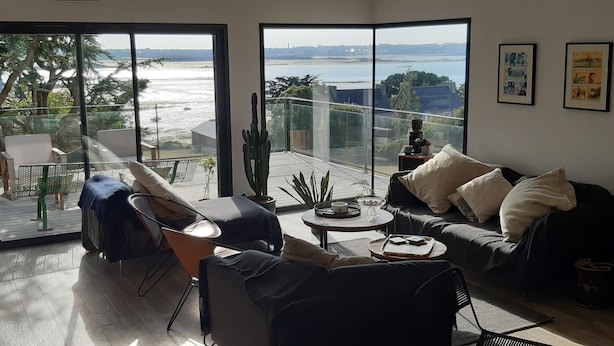 A modern living room with a large glass door leading to a balcony overlooking a body of water. - "Au gré des marées", panoramic sea view, beach 300 m, town 800 m. (Carantec)
