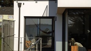 A modern building with a glass entrance, a wooden deck, and a metal railing. - "Au gré des marées", panoramic sea view, beach 300 m, town 800 m. (Carantec)