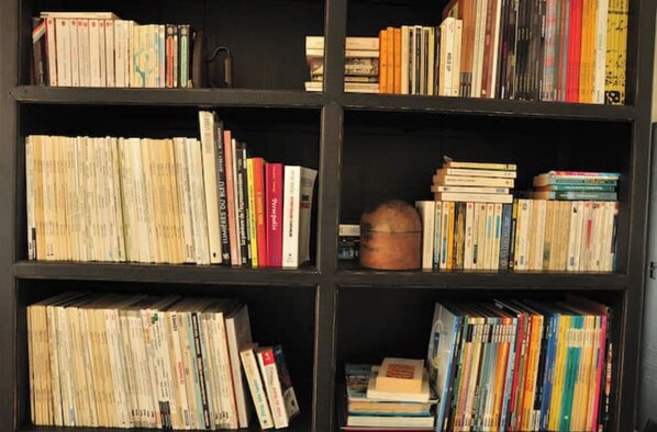 Kirjahylly, joka on täynnä erikokoisia ja -värisiä kirjoja.