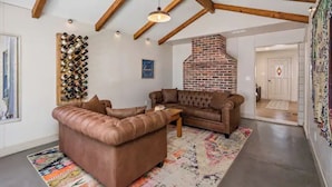 A living room with a brown leather sofa, a coffee table, and a brick fireplace.