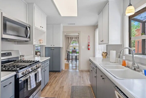 A modern kitchen with white cabinets, a stainless steel stove, and a large window.