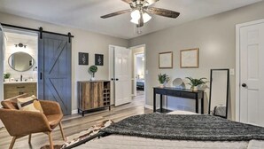 A bedroom with a bed, a ceiling fan, a sliding barn door, a desk, and a chair. - Chic Lilburn Getaway w/Media Room + Fire Pit (Lilburn)