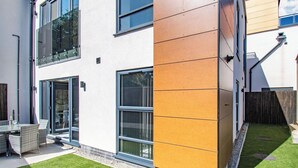Ein modernes, zweistöckiges Gebäude mit großen Fenstern, einer flachen Dachkonstruktion und einem gepflegten Rasen.
