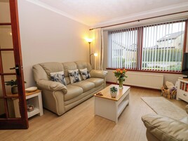 A living room with a beige sofa, a coffee table, a floor lamp, and a window with blinds.