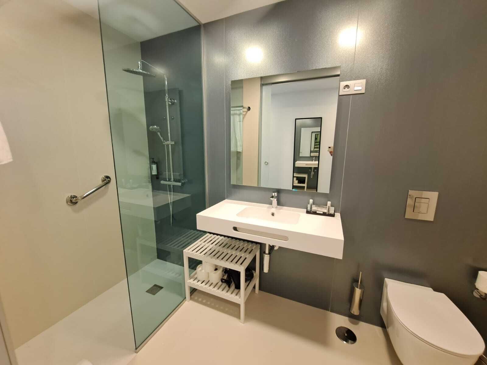 A modern bathroom with a glass-enclosed shower, a white sink, and a toilet.