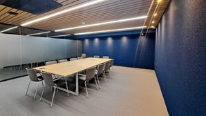 Una sala de conferencias con una larga mesa, sillas y una pared azul destacada.