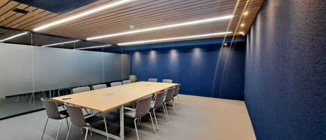 A conference room with a long table, chairs, and a blue accent wall.