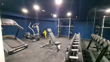 A gym with exercise equipment, a treadmill, and weightlifting stations.