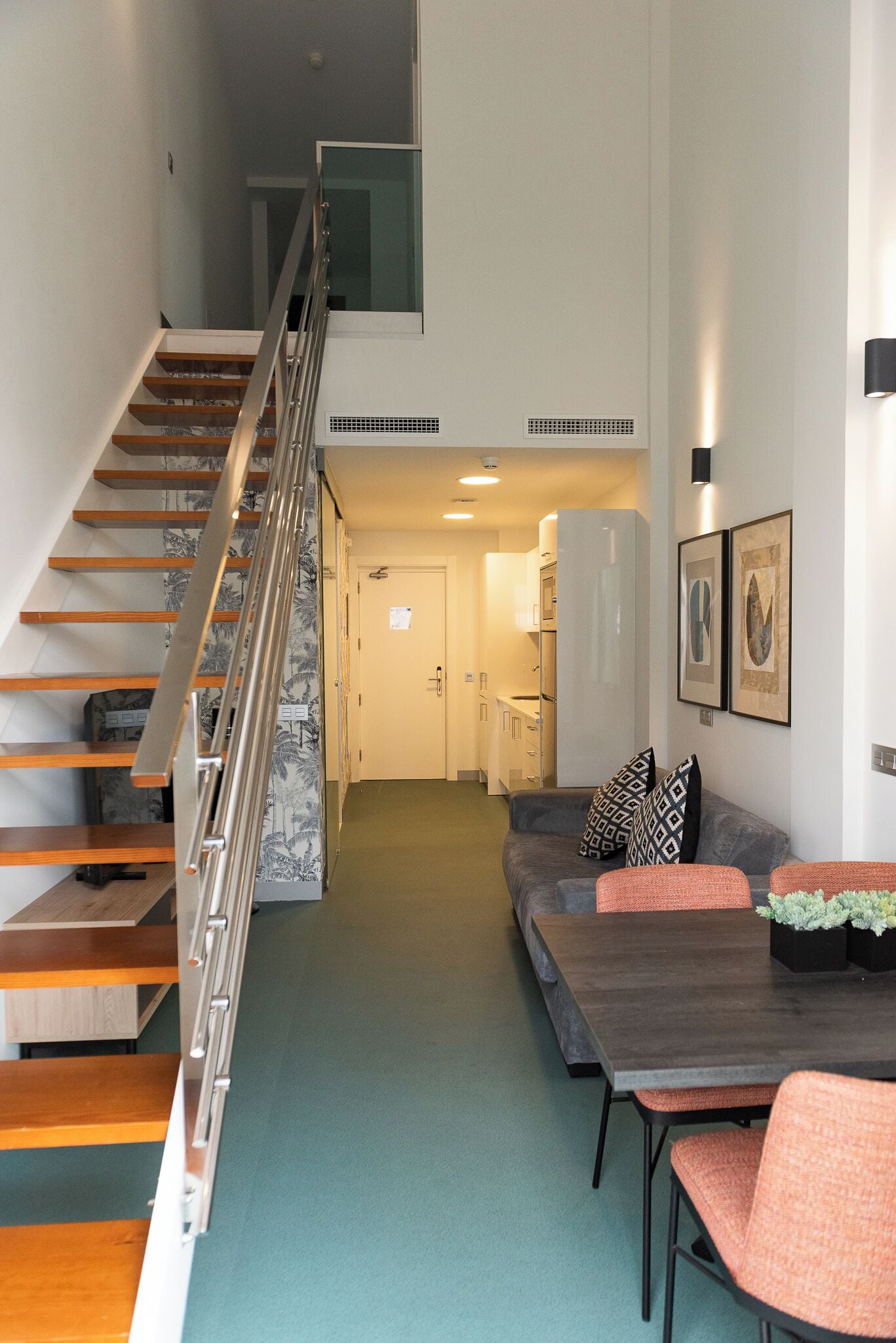 A modern interior with a staircase, a living area with a sofa and chairs, and a dining table.