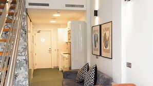 Un interior moderno con una escalera, un comedor con mesa y sillas, y una cocina al fondo.