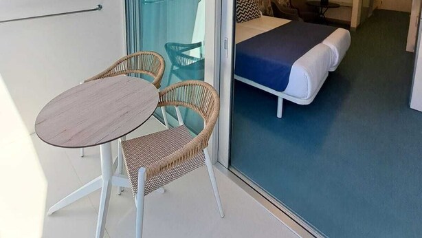 Una habitación moderna con cama, una mesita y sillas de mimbre.
