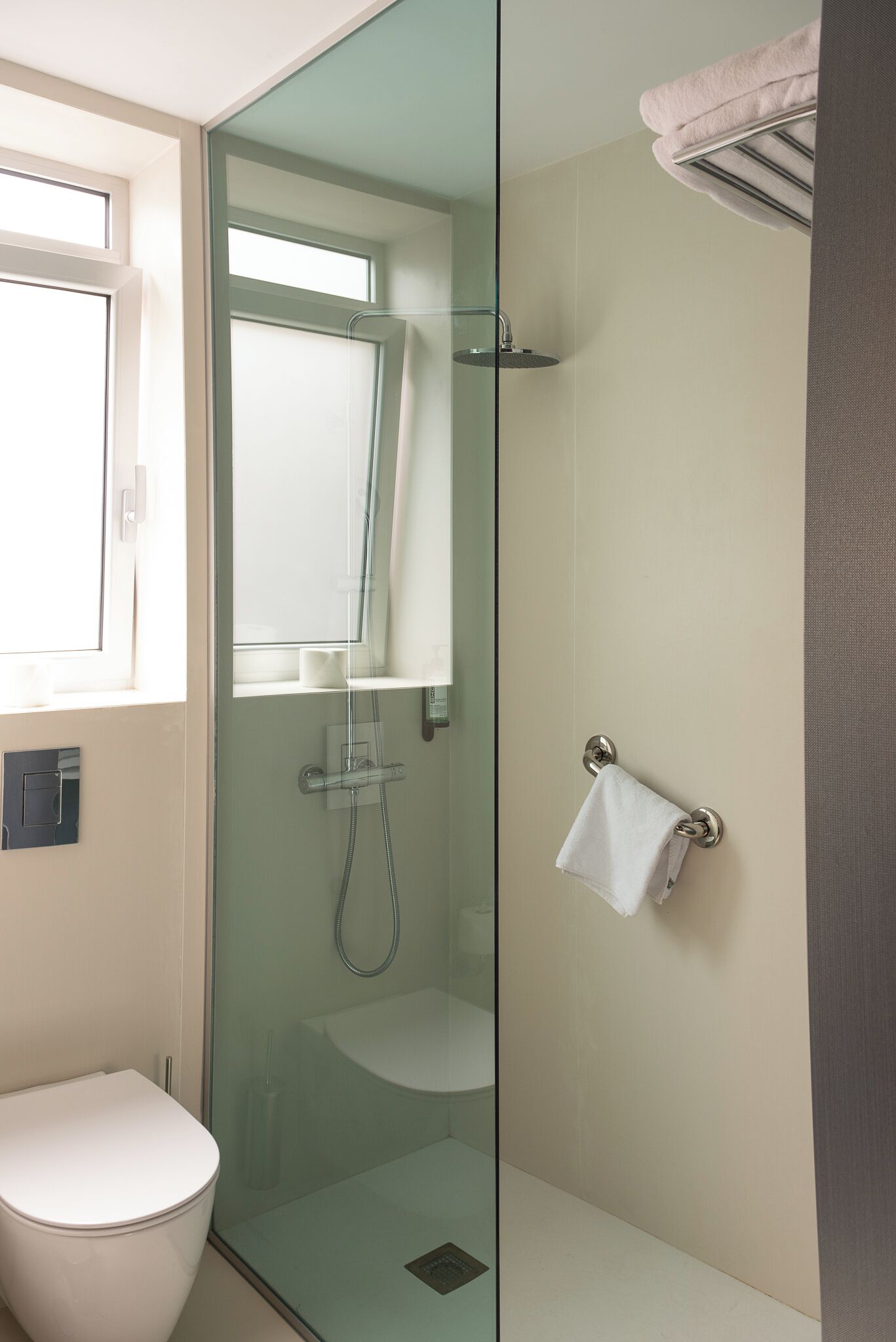 A modern bathroom with a glass-enclosed shower, a white toilet, and a towel rack.