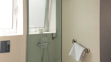 A modern bathroom with a glass-enclosed shower, a white toilet, and a towel rack.
