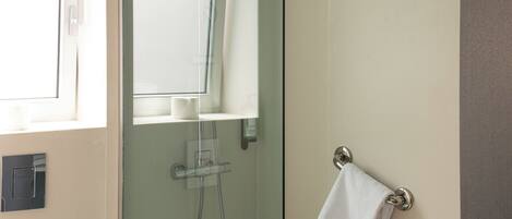 A modern bathroom with a glass-enclosed shower, a white toilet, and a towel rack.