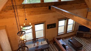 A wooden cabin interior with a dining area, a sofa, and a television. - Windrock Ridge Luxury Ethan Cabin: Ride-In Access, Sleeps 16. (oliver spring)