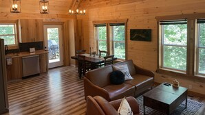 A wooden cabin interior with a kitchen, dining area, and living room. - Windrock Ridge Luxury Ethan Cabin: Ride-In Access, Sleeps 16. (oliver spring)
