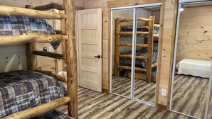 A wooden bunk bed room with a door and a mirror. - Windrock Ridge Luxury Ethan Cabin: Ride-In Access, Sleeps 16. (oliver spring)