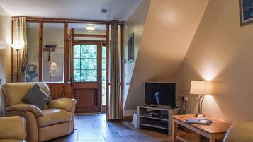 A cozy living room with a sofa, a television, and a wooden table.