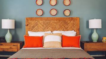 A bedroom with a wooden headboard, a bed with multiple pillows, two bedside tables with lamps, and a wall with circular woven decorations.