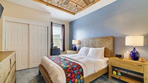 Un dormitorio con cama, mesitas de noche, escritorio y techo de vigas de madera.