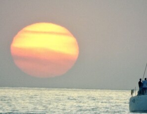 A sunset over the ocean with a boat in the foreground. - Pearl of Tranquility, 1 mile from beach and Old Town! (Bay St. Louis)