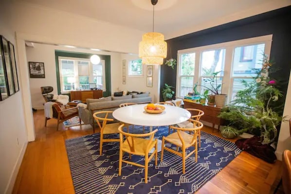 A dining area with a round table, chairs, and a hanging light fixture.