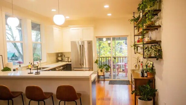 A modern kitchen with a central island, bar stools, and a dining area with a view of the outdoors. - Alberta Arts District 2 private bedrooms/bathroom (Portland)