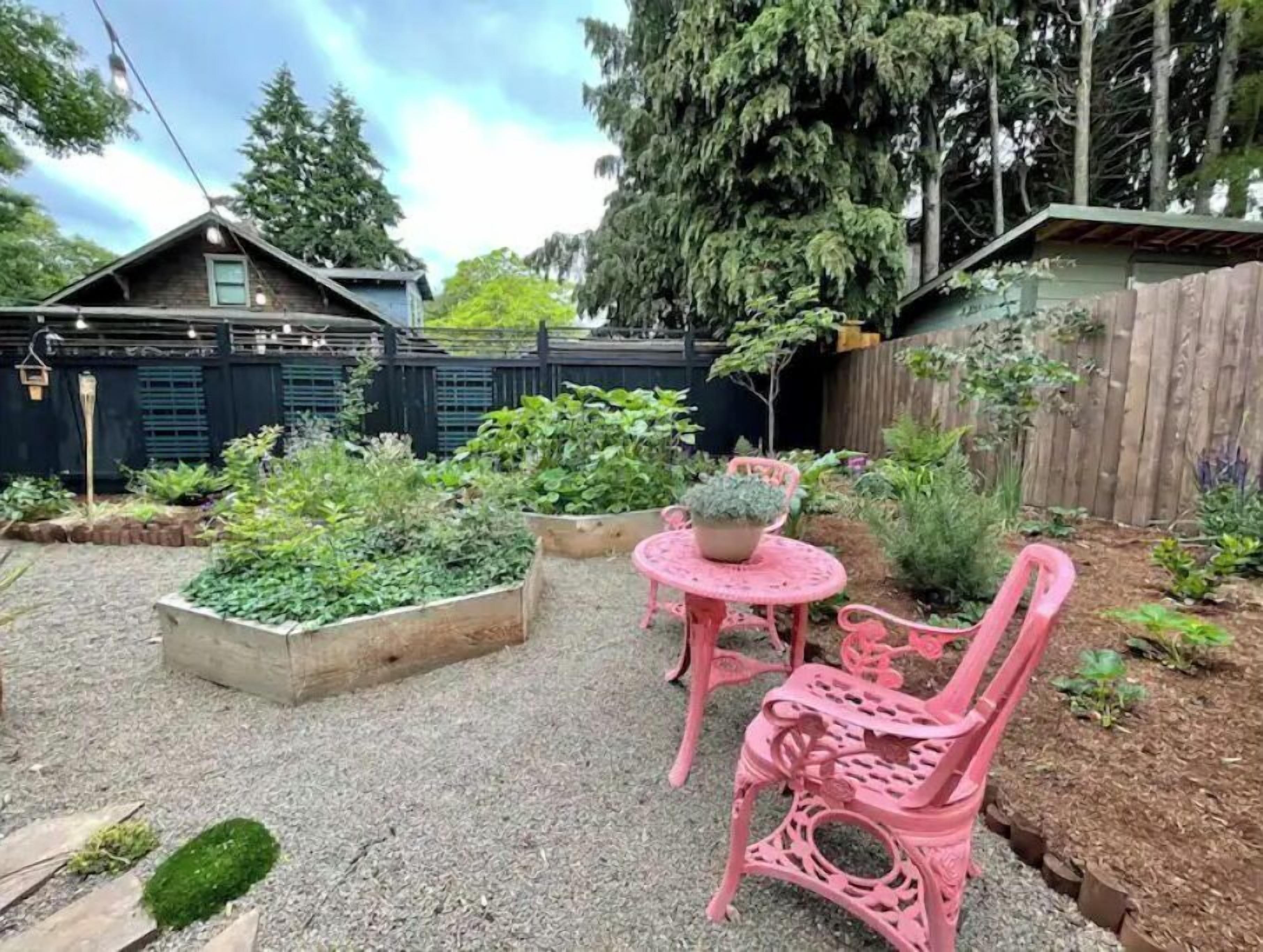 A garden patio with raised beds, a small table, and two chairs.