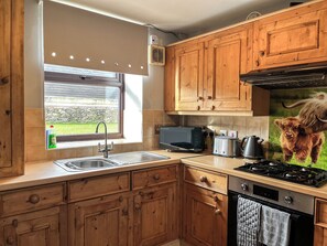 A kitchen with wooden cabinets, a microwave, toaster, kettle, and a stove.