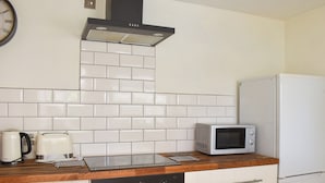 A kitchen with white tiled backsplash, a microwave, a toaster, and a stove. - 2 bedroom accommodation in Clanfield, near Petersfield (Clanfield, near Petersfield)