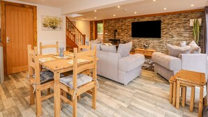 A spacious living area with a wooden dining table, two sofas, and a stone accent wall. - Little Lodge (King's Lynn)