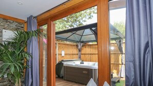 A cozy room with a wooden floor, a grey sofa, and a large window. - Little Lodge (King's Lynn)