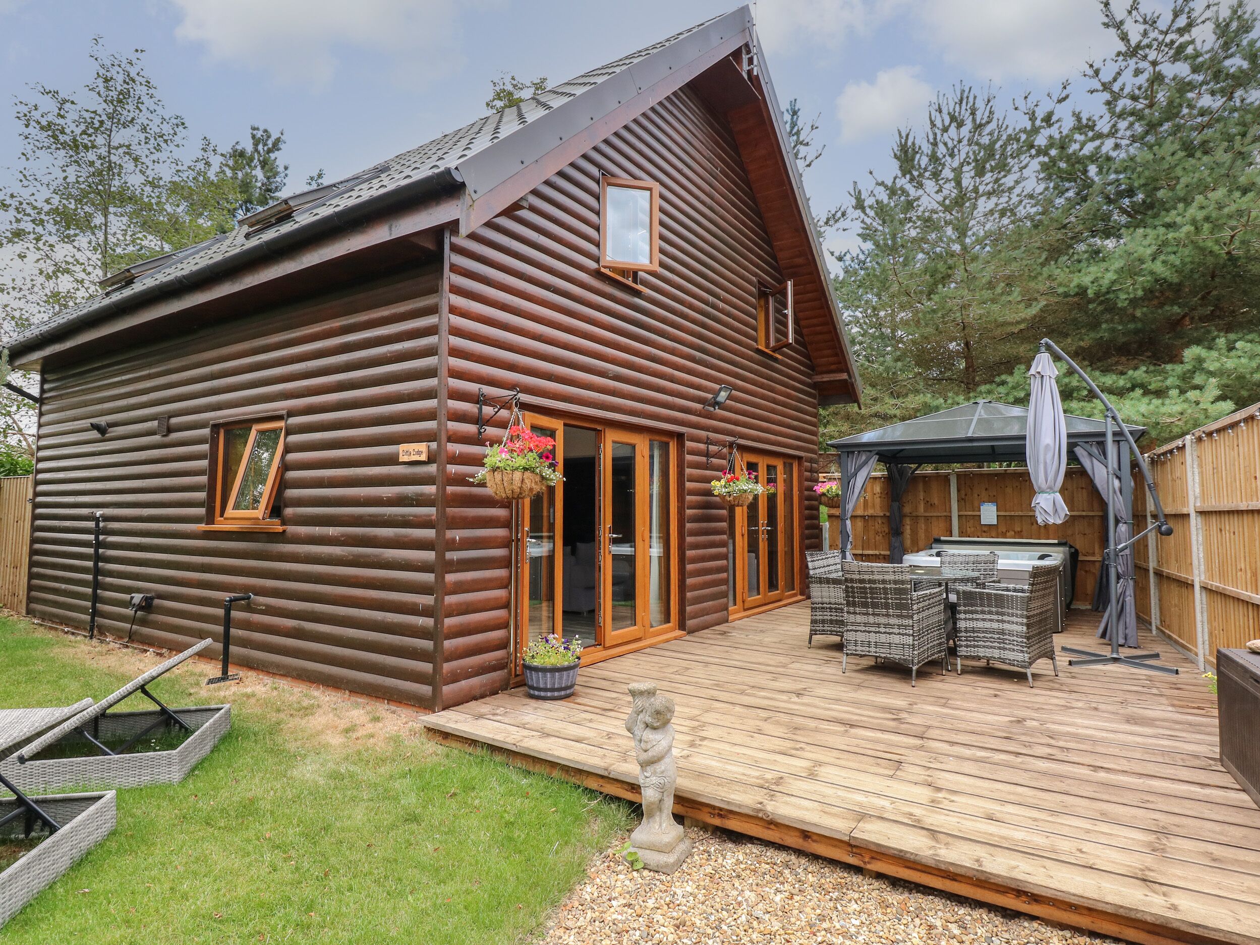 A log cabin with a deck, outdoor seating, and a hot tub.
